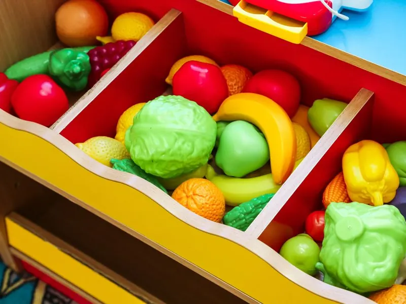Toy fruit and vegetables in a play-store bin.