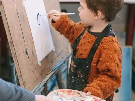 A child in a smock painting at an easel.