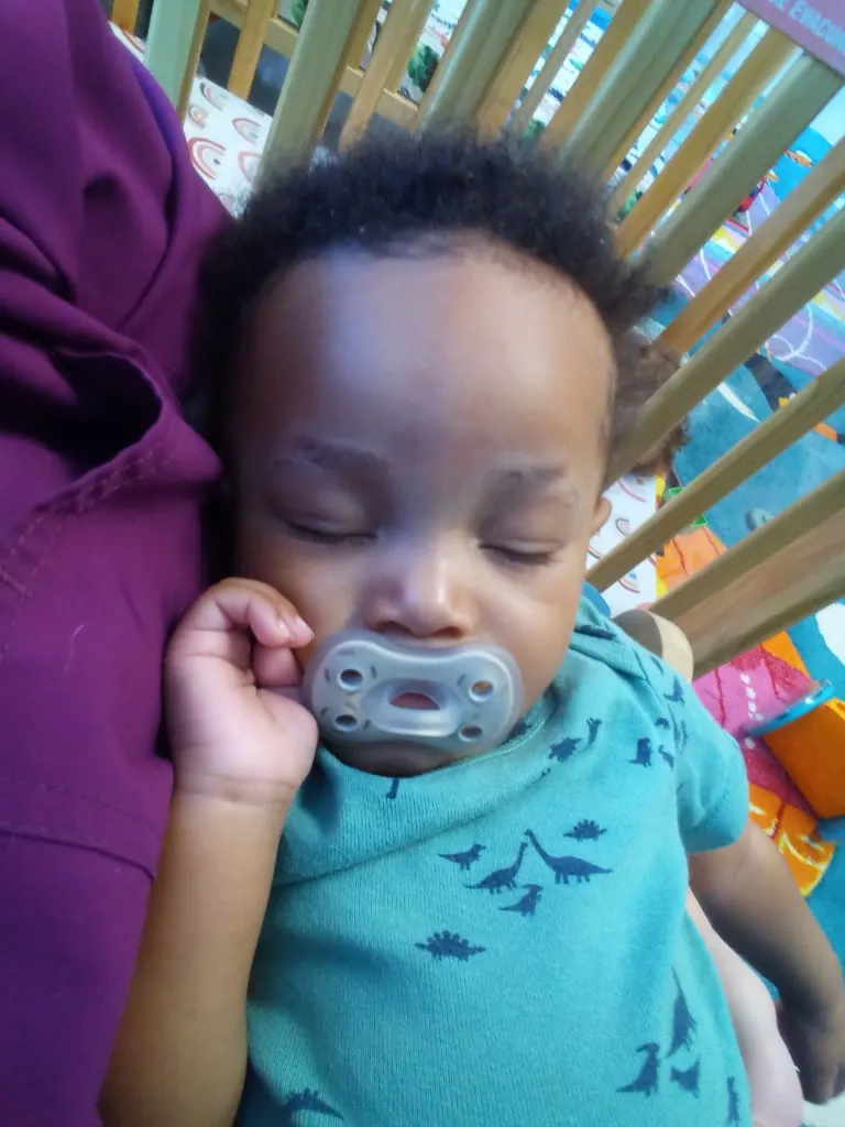 A baby asleep with a pacifier, held close.