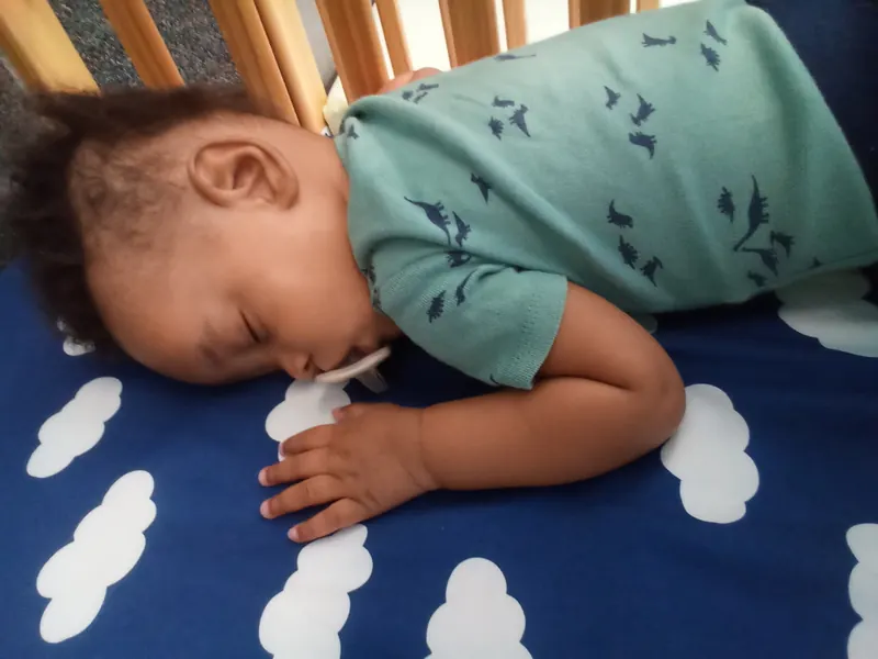 A baby asleep on a cloud-print mat.