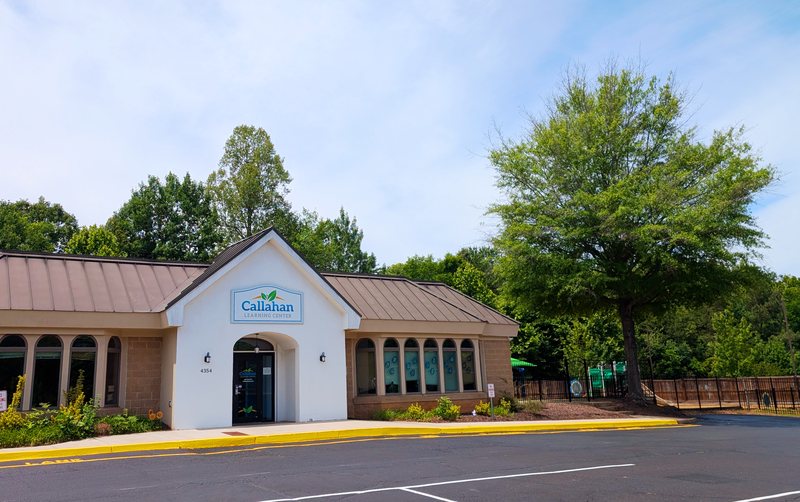 The Locust Grove center on a sunny day, a tan building with a gabled entrance carrying the Callahan logo, arched windows, and a shade tree.