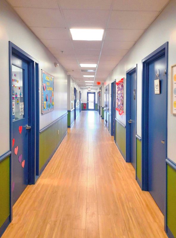 A bright Locust Grove hallway lined with blue classroom doors and children's artwork.