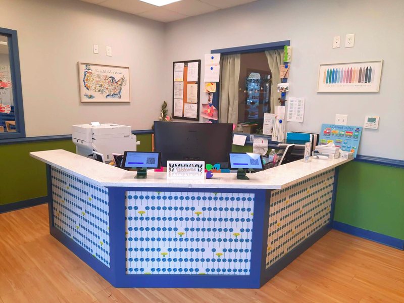 The Locust Grove front desk and sign-in area, with check-in tablets, a U.S. map, and cheerful blue-and-green walls.
